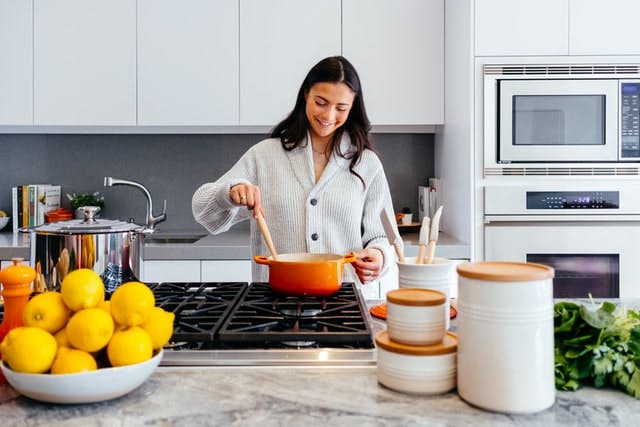 woman cooking and looking down at pot smiling
