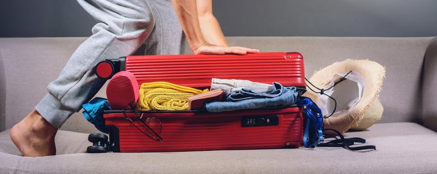 woman packing red suitcase to travel