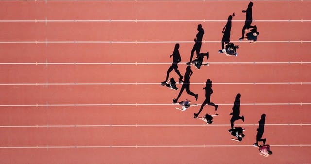 A birds eye view of a team walking in a v-formation on a running track