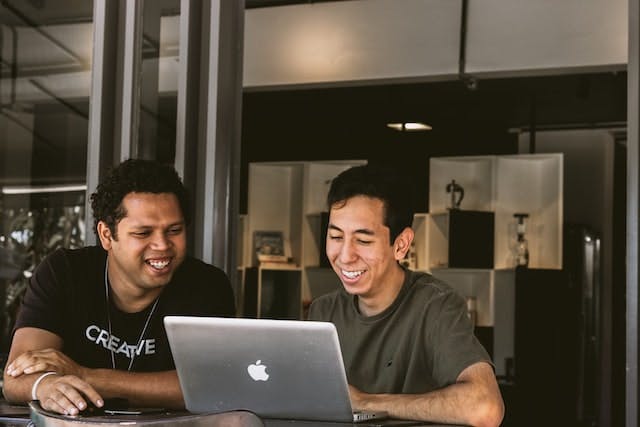 two people smiling and looking at a laptop screen