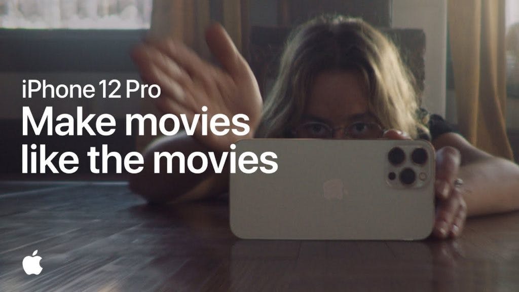 Ad for iPhone 12 Pro. The ad has a picture of a young woman lying on the floor with her phone, filming something. The ad says "iPhone 12 Pro "Make movies like the movies."