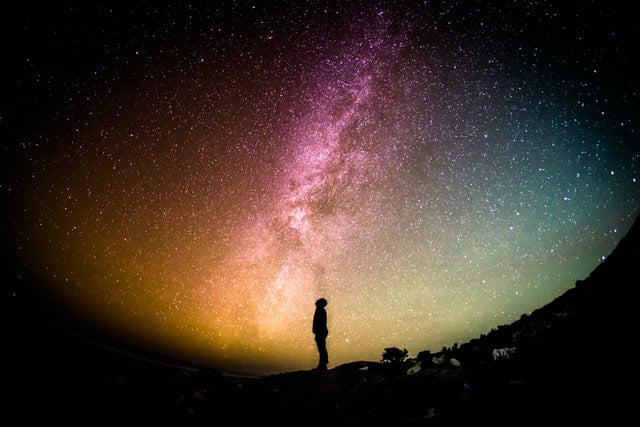 Silhouette of person looking up at starry sky