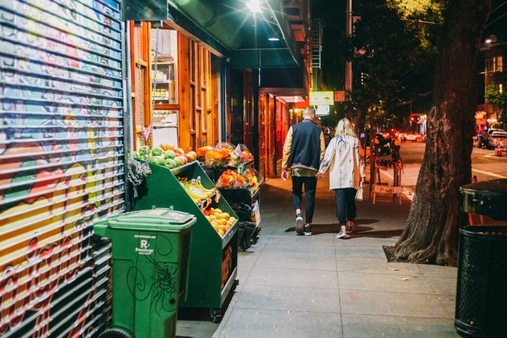 couple walking next to grocery store at night
