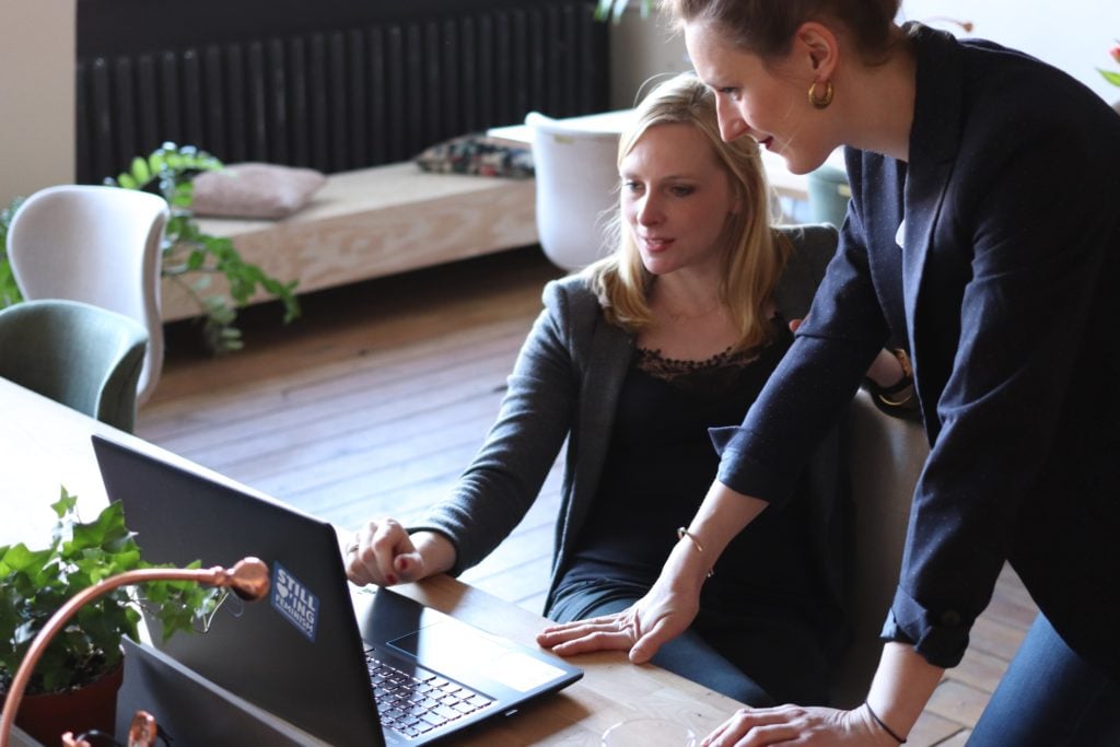 two women sitting around a computer