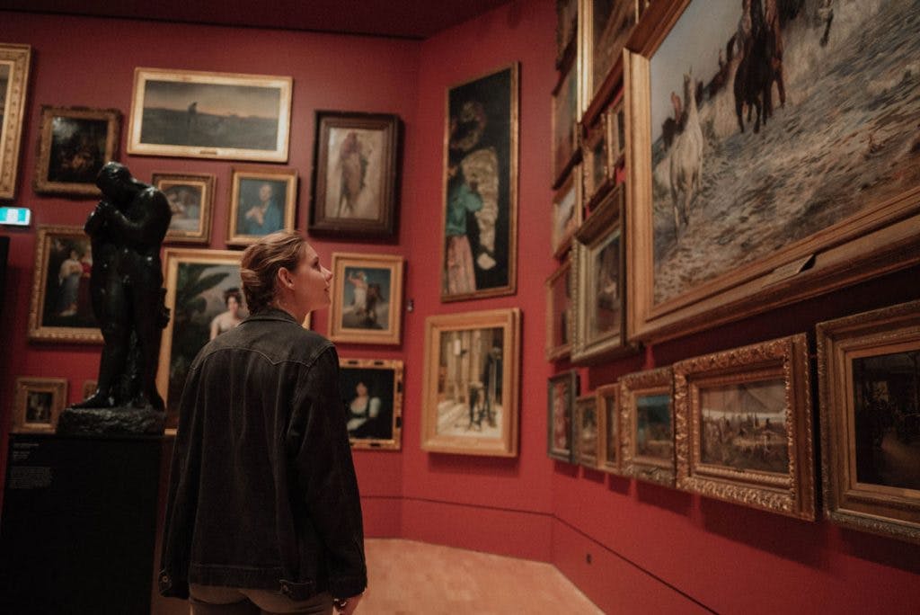 woman admiring paintings at museum