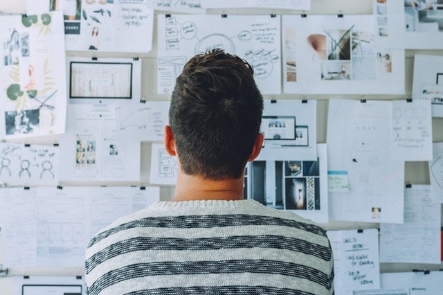 person standing with back to camera looking at a wall full of planning papers
