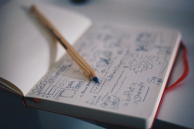 notebook with blue scribbles and pencil on top