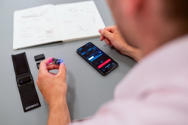 view from behind shoulder of man holding a computing chip with a phone and notebook on the table in front of him