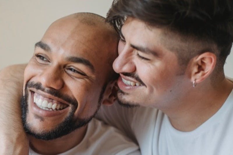 close up of two men. they are embracing and laughing
