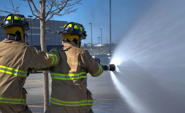 two firefighters holding open firehose