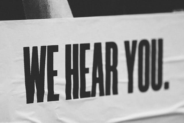 a white banner with black lettering that says "we hear you"