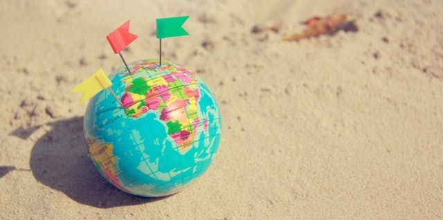Globe on the sand with little flags