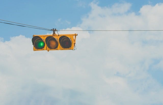 green traffic light against backdrop of clouds