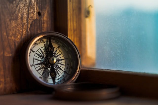 old fashioned pocket compass sitting against windowsill