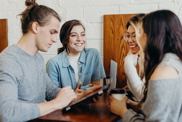 group of four young professionals smiling and talking
