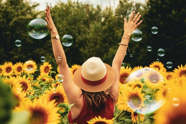 person standing in a field of sunflowers with arms outstretched