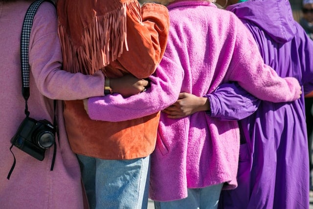 Row of people's backs, they have their arms around each other
