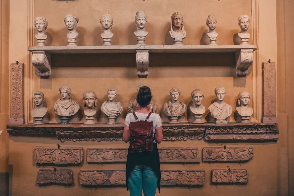 woman looking at shelves with old sculptures